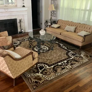 An elegant living room featuring a beige sofa, matching armchair, glass coffee table, ornate rug, and a fireplace with a white mantel.