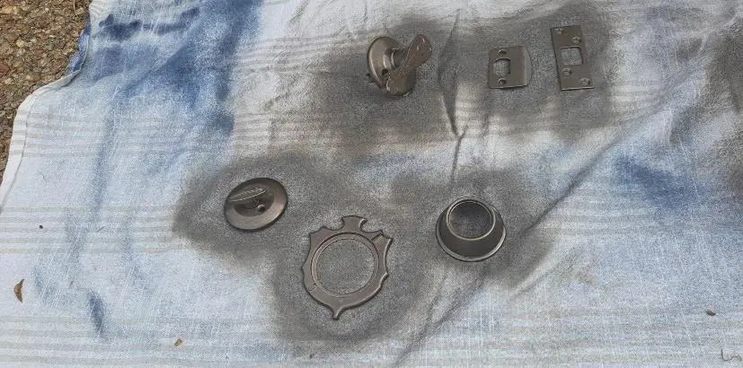 Various metal door hardware pieces displayed on a worn blue tarp.